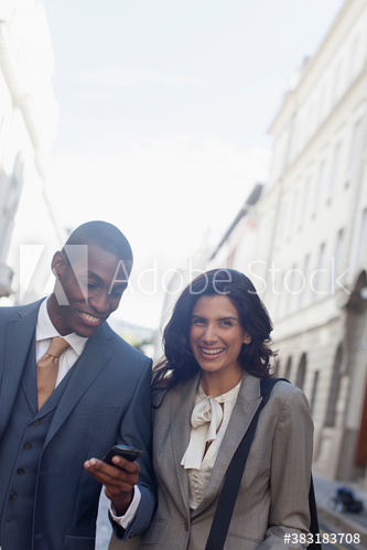 Portrait smiling business people using smart phone in city street
