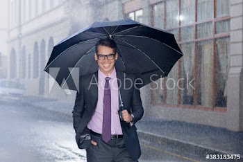 Portrait smiling businessman with umbrella on rainy street