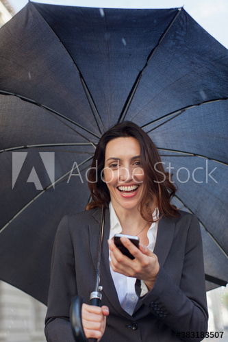 Portrait smiling businesswoman with umbrella using smart phone