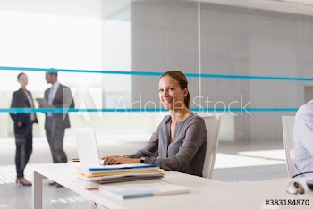 Portrait smiling corporate businesswoman working at laptop in office