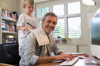 Portrait smiling father working in home office with son