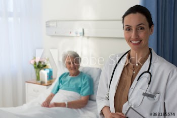 Portrait smiling female doctor checking on senior patient in hospital room