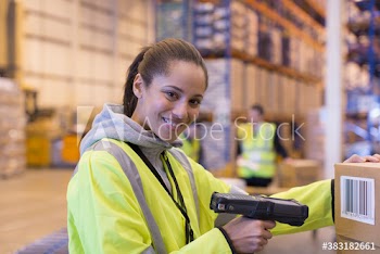 Portrait smiling female worker scanning box in distribution warehouse