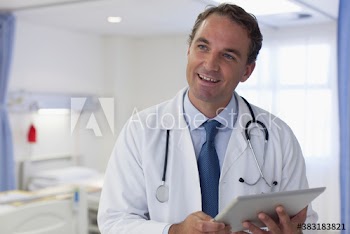 Portrait smiling male doctor with digital tablet making rounds in hospital