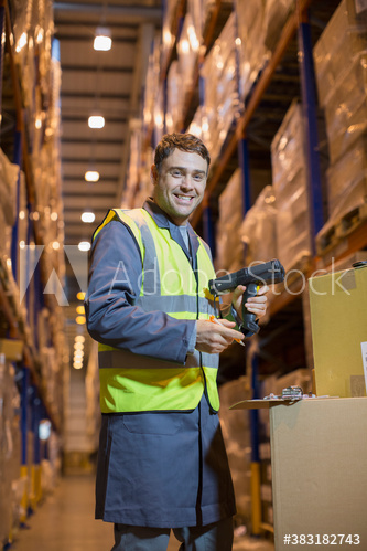 Portrait smiling male worker scanning boxes in distribution warehouse