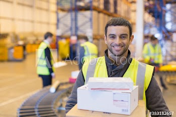 Portrait smiling male worker with packages in distribution warehouse