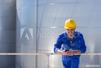 Portrait smiling male worker with smart phone in hard hat and coveralls