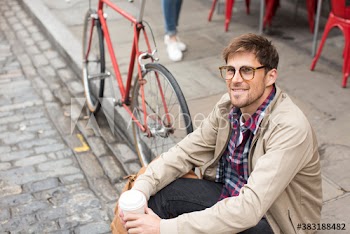 Portrait smiling man drinking coffee on curb