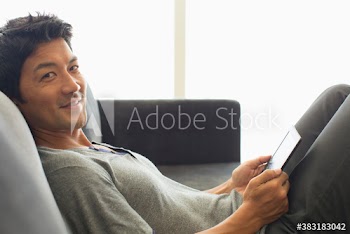 Portrait smiling man using digital tablet on sofa