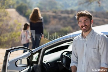 Portrait smiling man with family outside car at sunny roadside