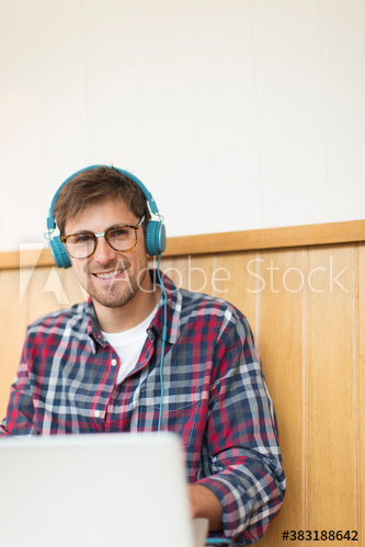 Portrait smiling man with headphones working at laptop in cafe