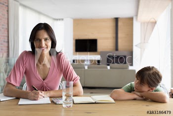 Portrait smiling mother working at dining table with daughter