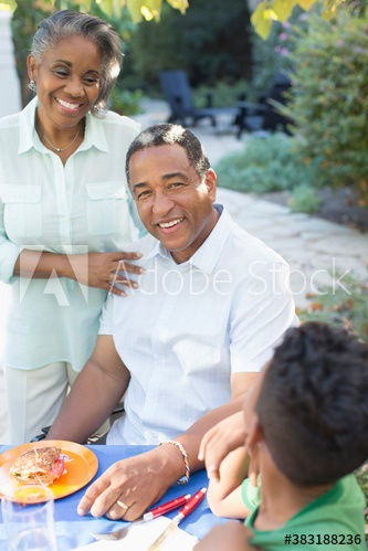 Portrait smiling senior couple eating lunch on patio with grandson