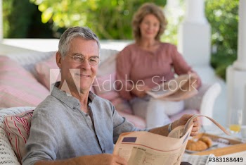 Portrait smiling senior man reading newspaper on patio