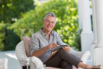 Portrait smiling senior man using digital tablet on patio