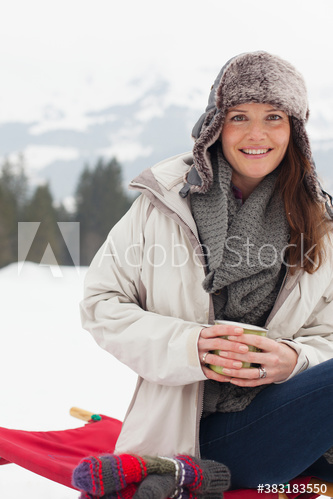 Portrait smiling woman drinking hot cocoa in snowy field