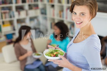 Portrait smiling woman eating salad with friends in living room