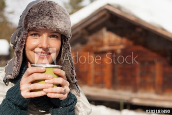 Portrait smiling woman in fur hat drinking coffee outside sunny cabin