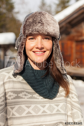 Portrait smiling woman in fur hat outside sunny cabin