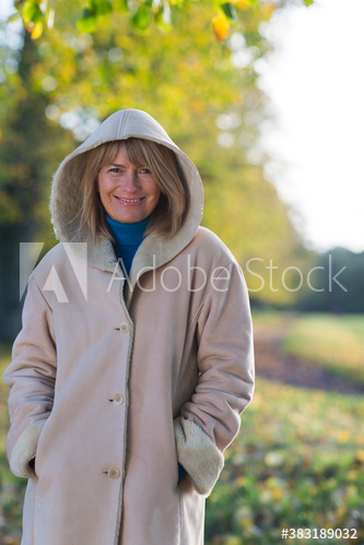 Portrait smiling woman in hooded coat in autumn park