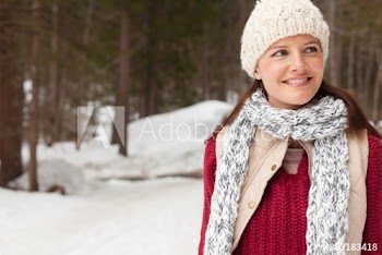 Portrait smiling woman in knit hat and scarf in snowy woods