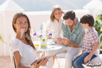 Portrait smiling woman using digital tablet on balcony with family
