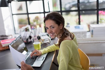 Portrait smiling woman working at laptop in home office
