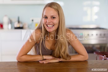 Portrait smiling young blonde woman at kitchen table