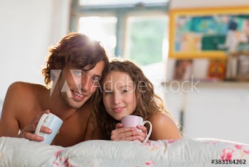 Portrait smiling young couple drinking coffee on bed