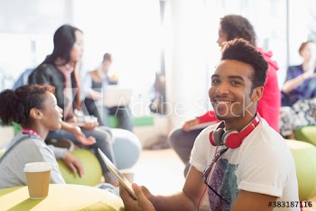 Portrait smiling young male college student using digital tablet