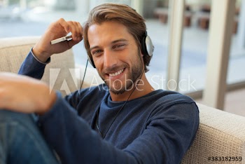 Portrait smiling young man listening to music with headphones on sofa