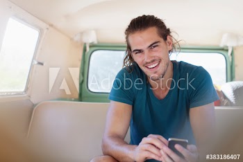 Portrait smiling young man using smart phone inside van
