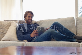 Portrait smiling young man with digital tablet relaxing on sofa