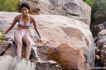 Portrait smiling young woman in bikini on rocks