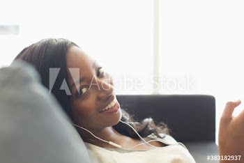 Portrait smiling young woman listening to music with headphones on sofa