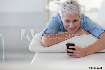 Portrait smiling young woman relaxing on sofa with smart phone