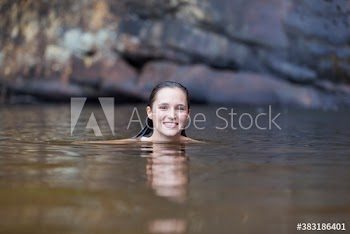 Portrait smiling young woman swimming in lake