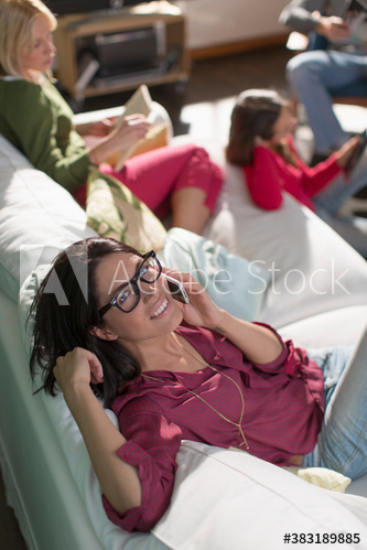 Portrait smiling young woman talking on smart phone on sofa