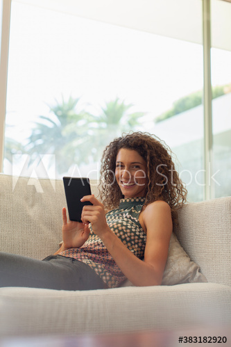 Portrait smiling young woman using digital tablet on sofa