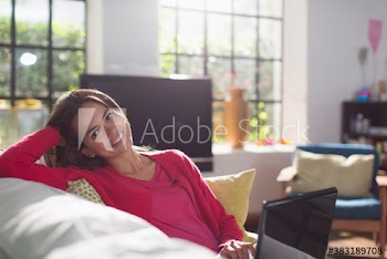 Portrait smiling young woman using laptop on sofa
