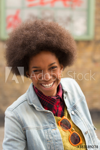 Portrait smiling young woman with afro in denim jacket