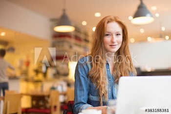 Portrait smiling young woman working at laptop in cafe