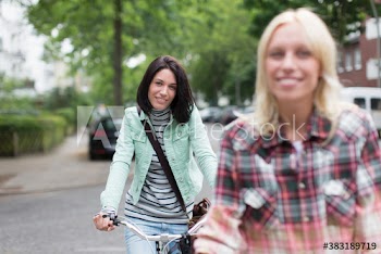 Portrait smiling young women riding bicycles on city street