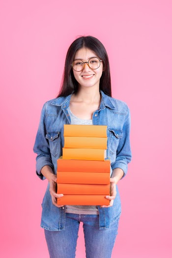 Portrait teenage pretty girl holding stack of books and smiley on pink, education teenge concept Free Photo