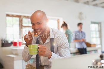 Portrait young businessman eating toast and drinking coffee in kitchen