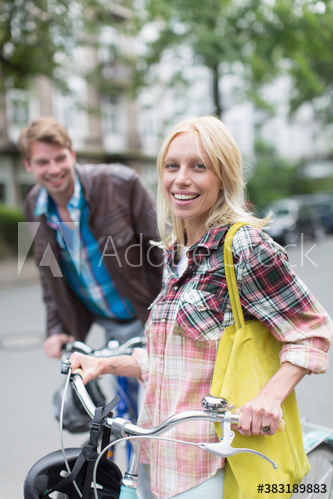 Portrait young couple with bicycles on street