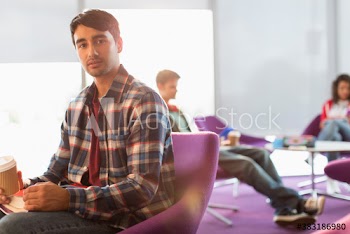 Portrait young man with coffee in student lounge