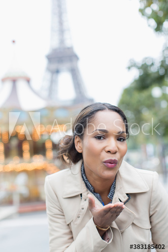 Portrait young woman blowing kiss in front of Eiffel Tower, Paris