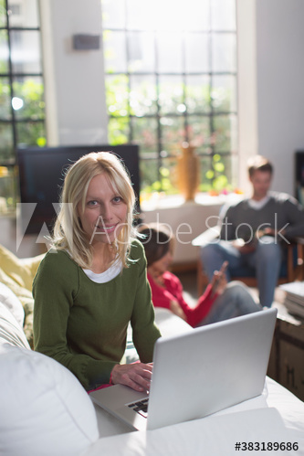 Portrait young woman using laptop on sofa