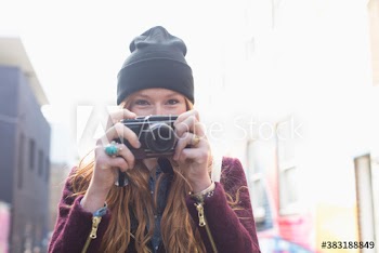 Portrait young woman with camera on sunny street